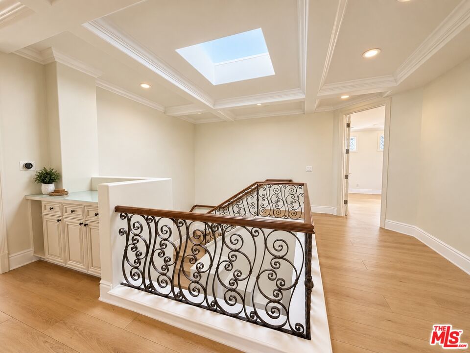 Interior landing with a skylight, built-in cabinet, and ornate wrought-iron stair railing.