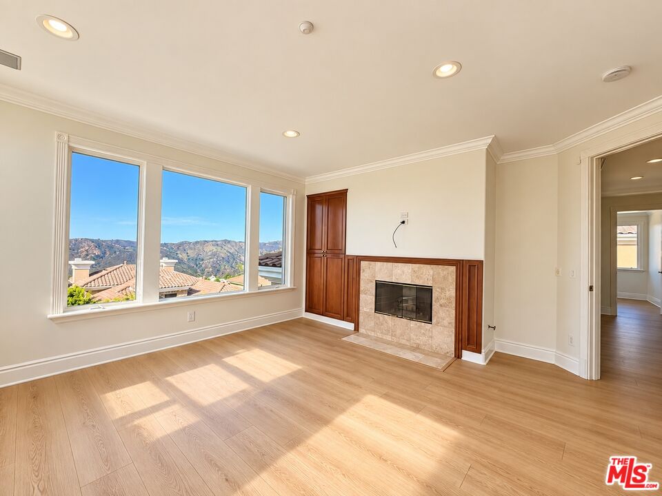 Empty living room with a tiled fireplace, large windows, and mountain views.