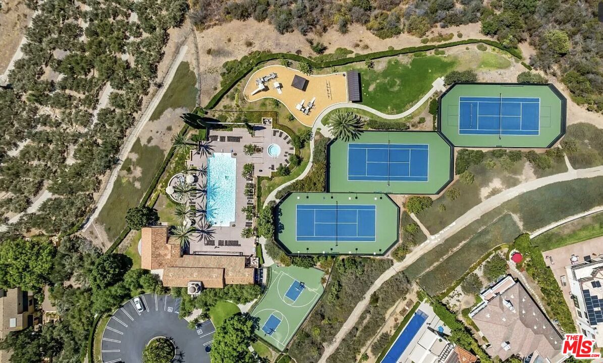 Aerial view of a property with a pool, tennis courts, basketball courts, and landscaped paths.