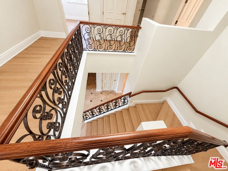 Multi-level staircase with light wood treads and ornate wrought-iron railings.