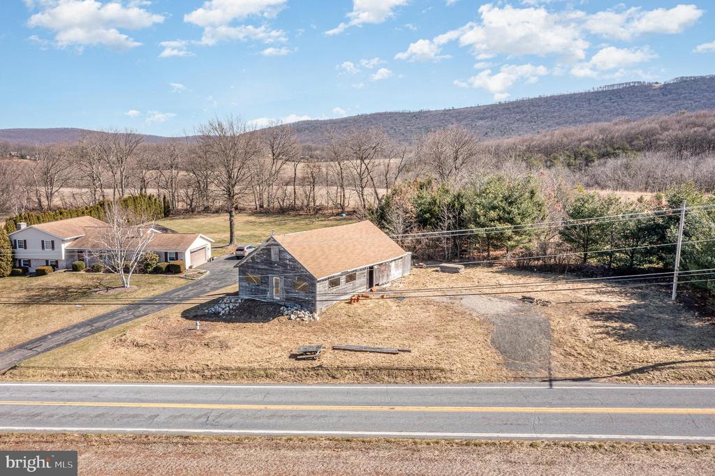 Rural property with a large barn, separate house, open land, and wooded hills beyond.