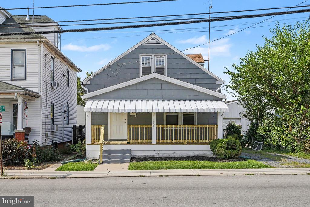 Gray-sided house with a covered front porch, white awning, and yellow railing.