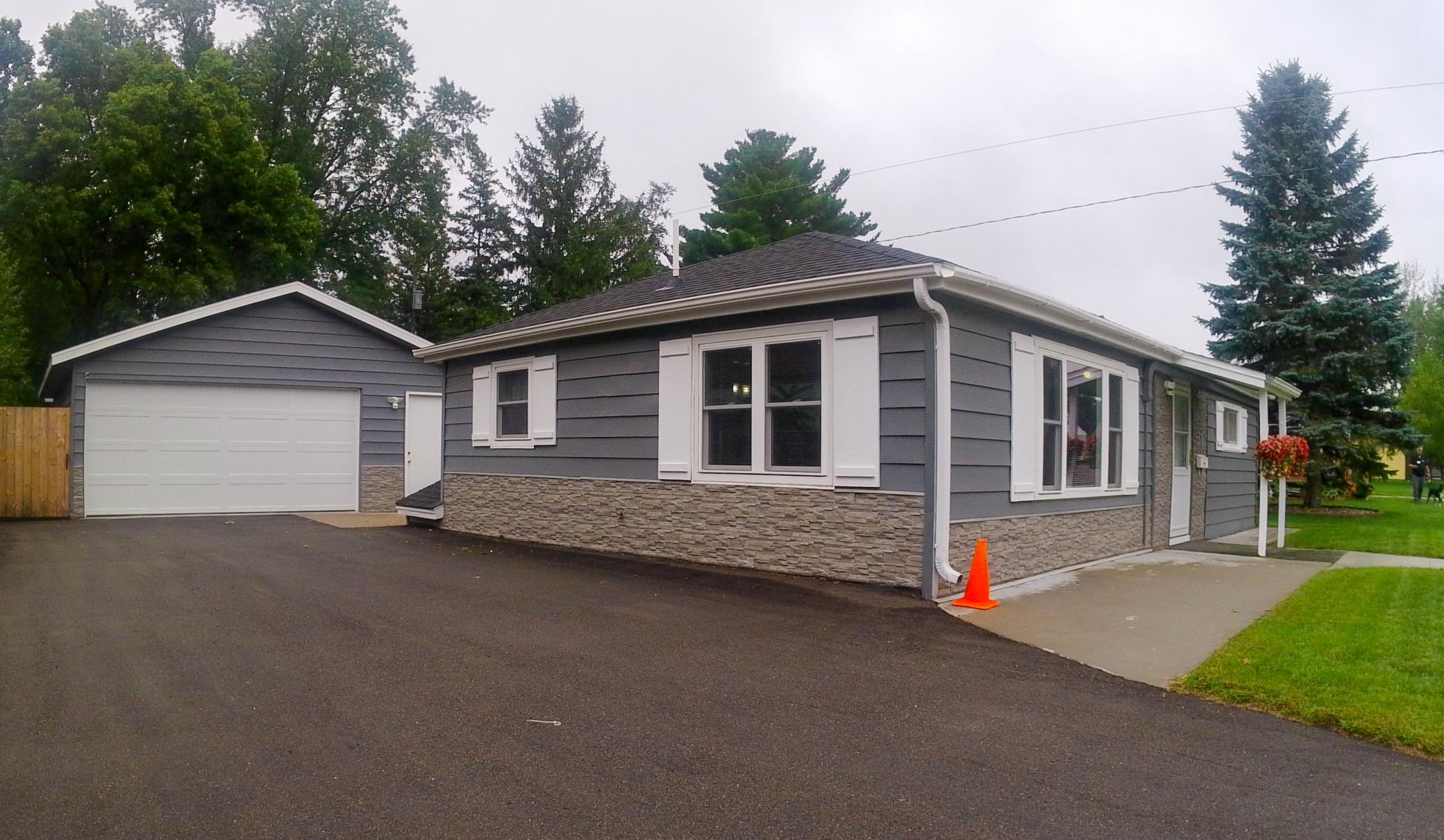 Gray single-story house with white trim, stone veneer, and an attached two-car garage.