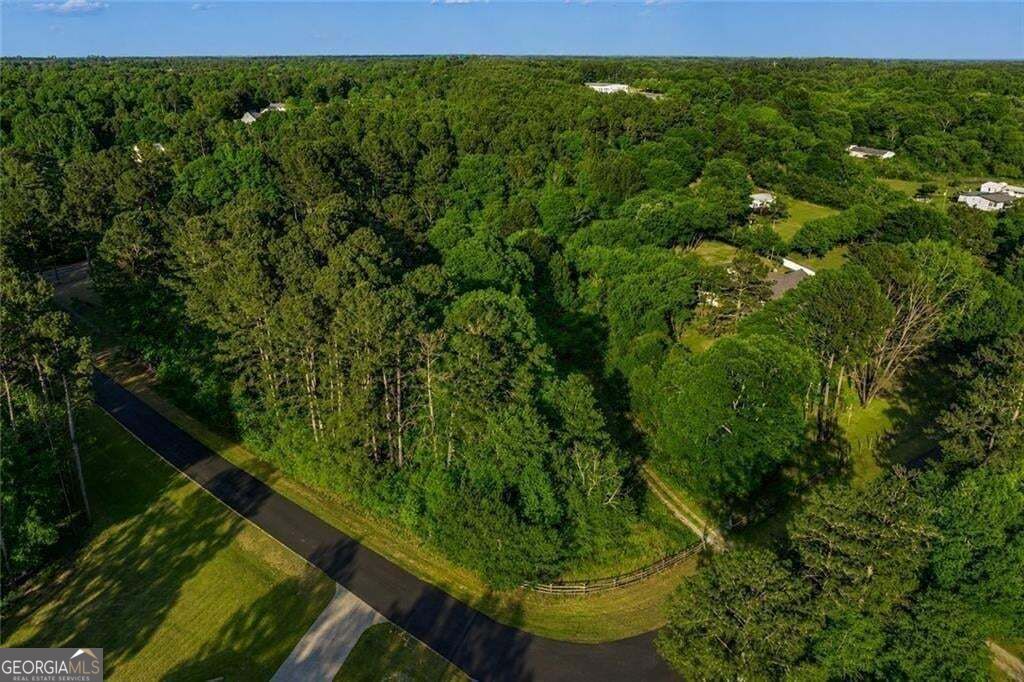 Aerial view of a wooded property beside a curving paved road.