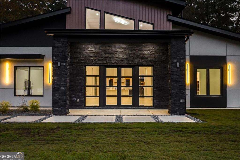 Modern property entrance with a dark stone surround, glass doors, and warm exterior lighting.