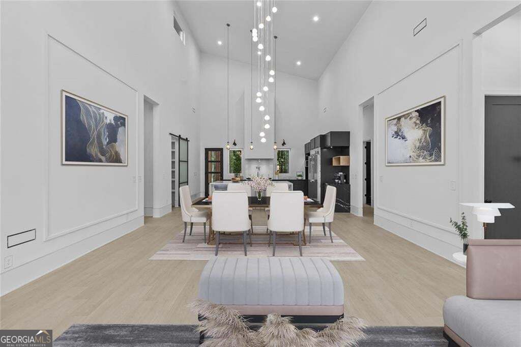Dining area with a long table beneath hanging globe lights, opening into a kitchen with black cabinetry.