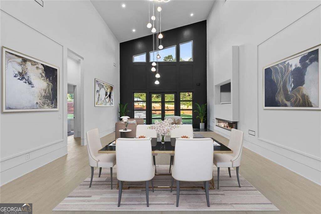 Furnished dining room with a tall black accent wall, pendant lights, and glass doors.