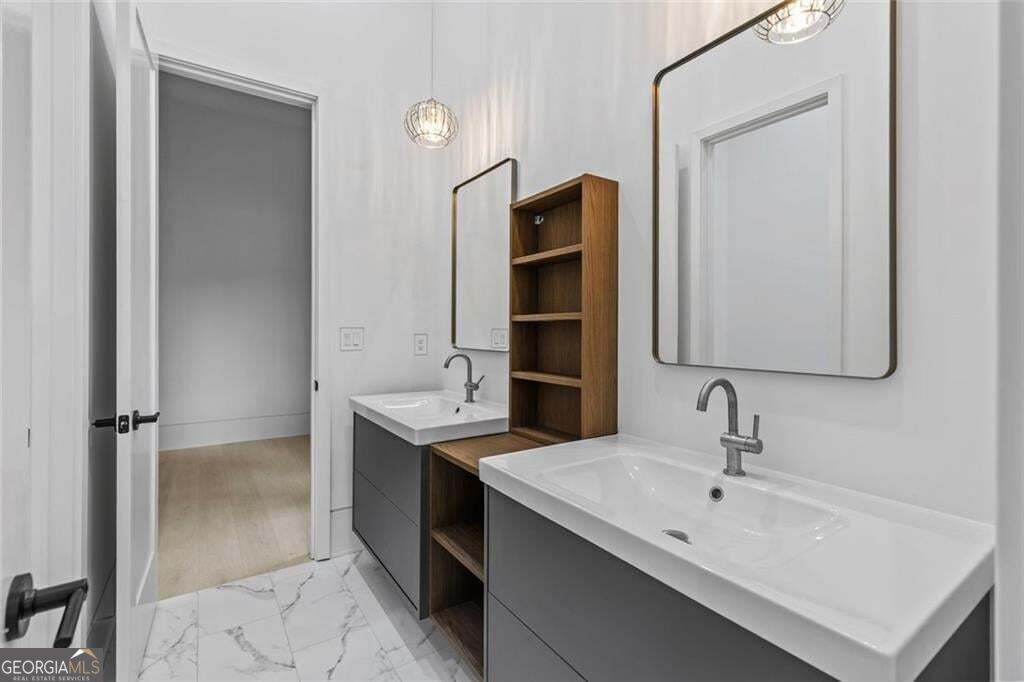 Bathroom with double sinks, gray vanities, and open wood shelving between the mirrors.