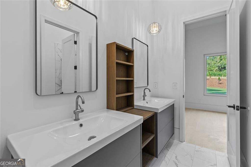 Bathroom with twin sinks, large mirrors, and wood shelving beside an open doorway.