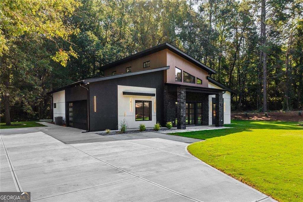 Modern two-story home with a broad concrete driveway, green lawn, and mature trees.