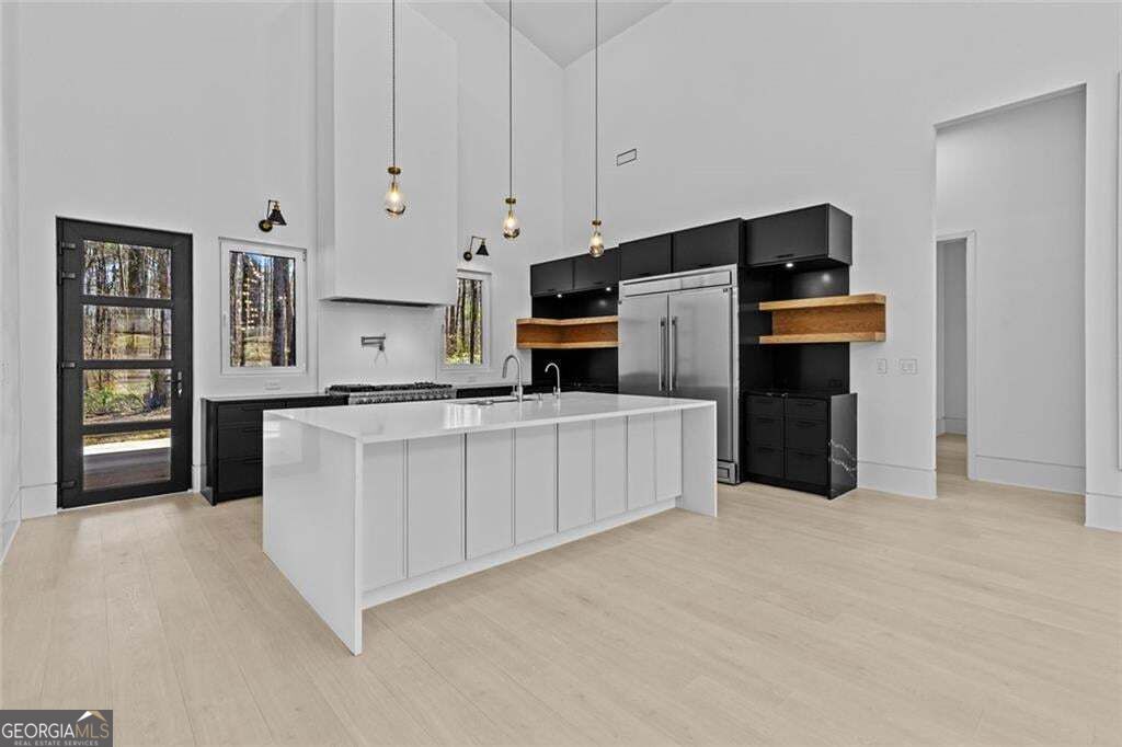 Modern kitchen with a large white island, black cabinets, and stainless steel refrigerator.