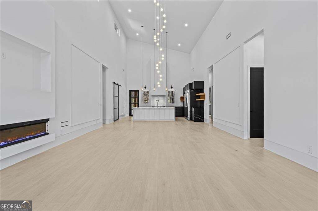 Open living area with a linear fireplace, soaring ceilings, and a kitchen island.