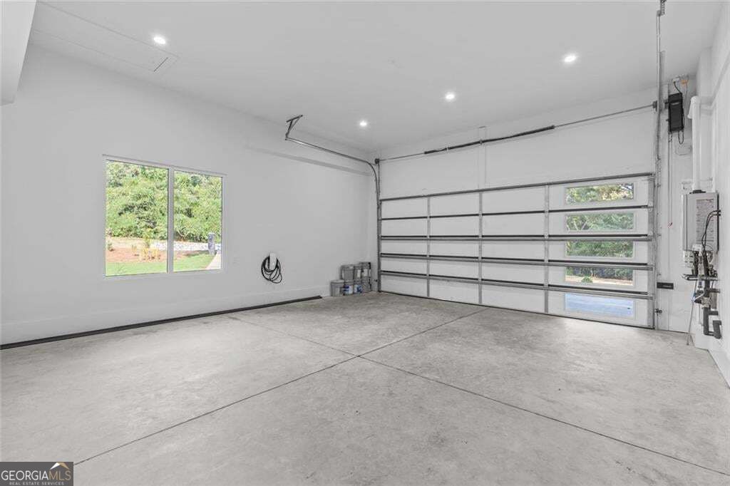 Empty garage with a concrete floor, large windowed overhead door, and side window.