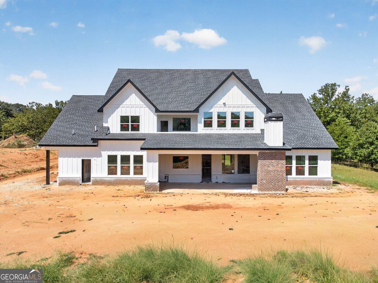 Two-story white house under construction with multiple gables and a dark shingle roof.