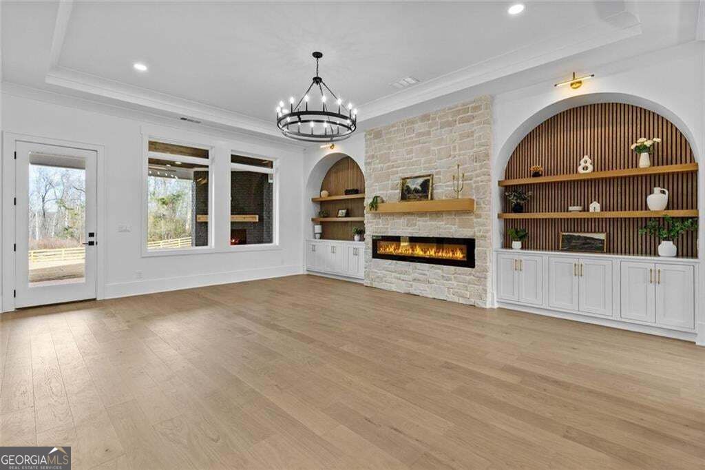 Living room with a stone fireplace, arched built-in shelves, and wide-plank wood flooring.
