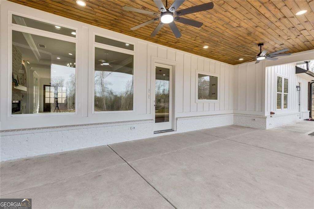 Covered patio with a wood-plank ceiling, two ceiling fans, and large windows.