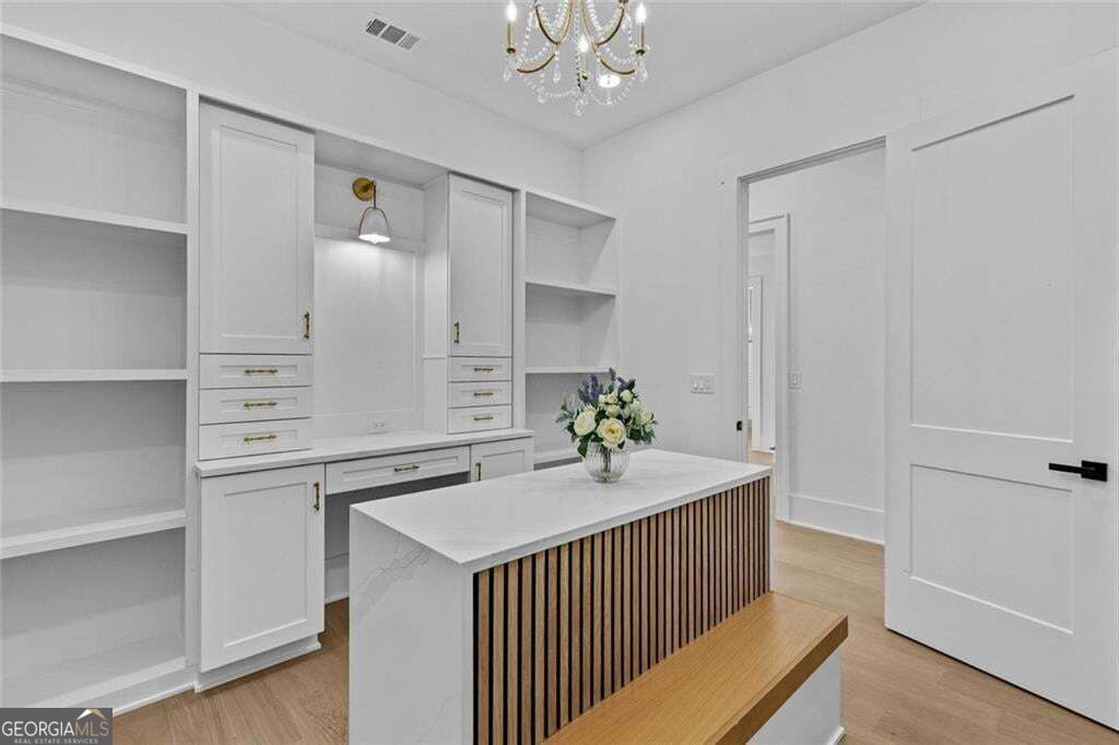Bright home office with built-in white cabinetry and a wood-slat desk island.