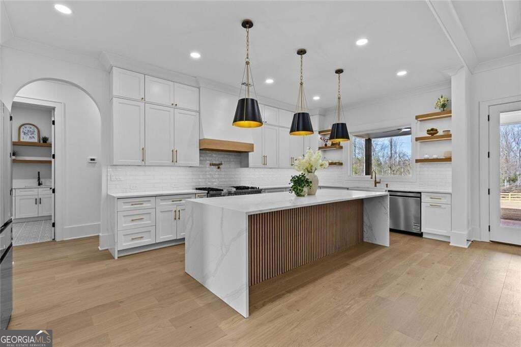 Modern white kitchen with a large wood-slat island and three black pendant lights.