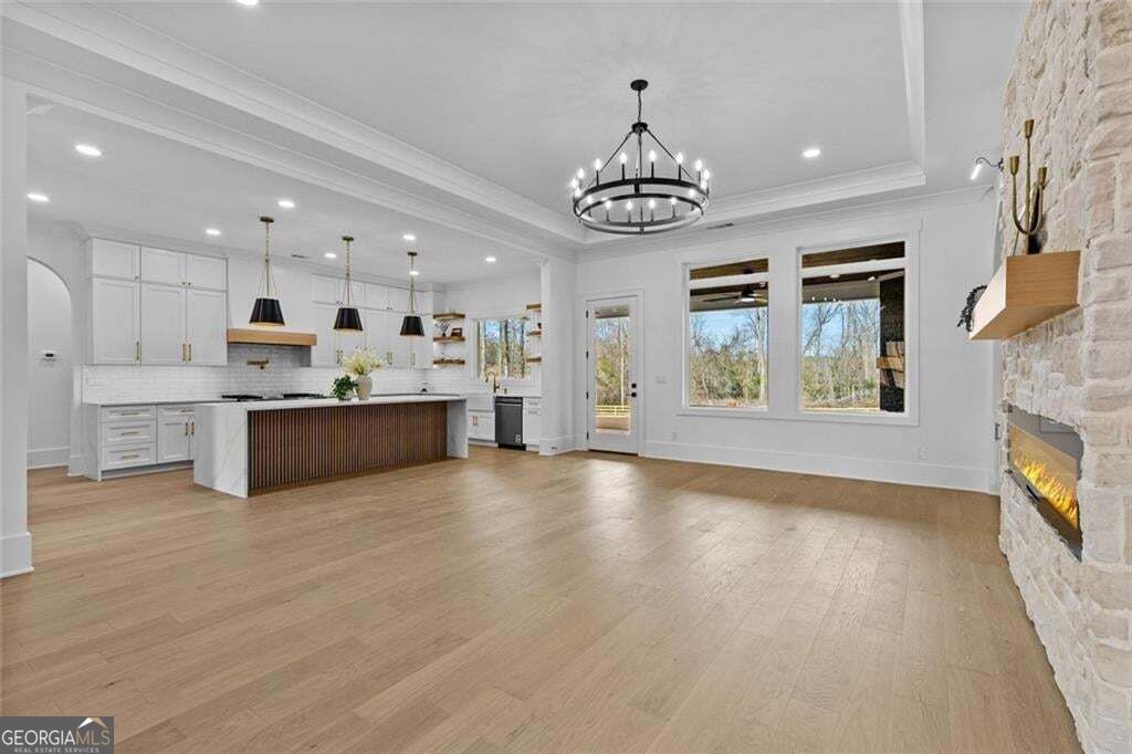 Open kitchen and living area with a large island, tall windows, and a stone fireplace.