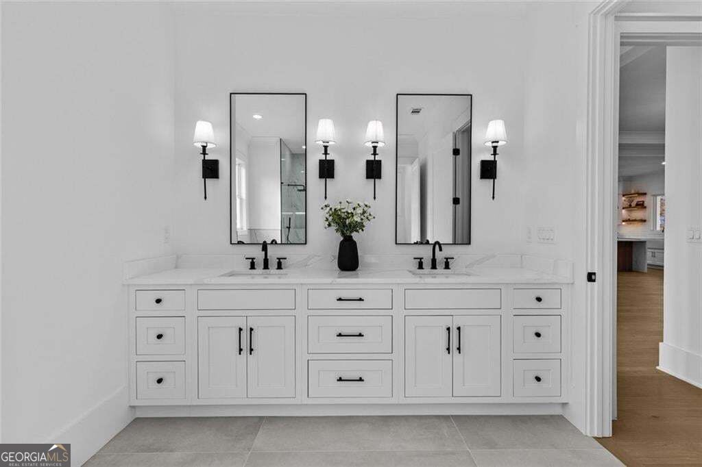 Bathroom with a long double-sink vanity, paired mirrors, black fixtures, and wall sconces.