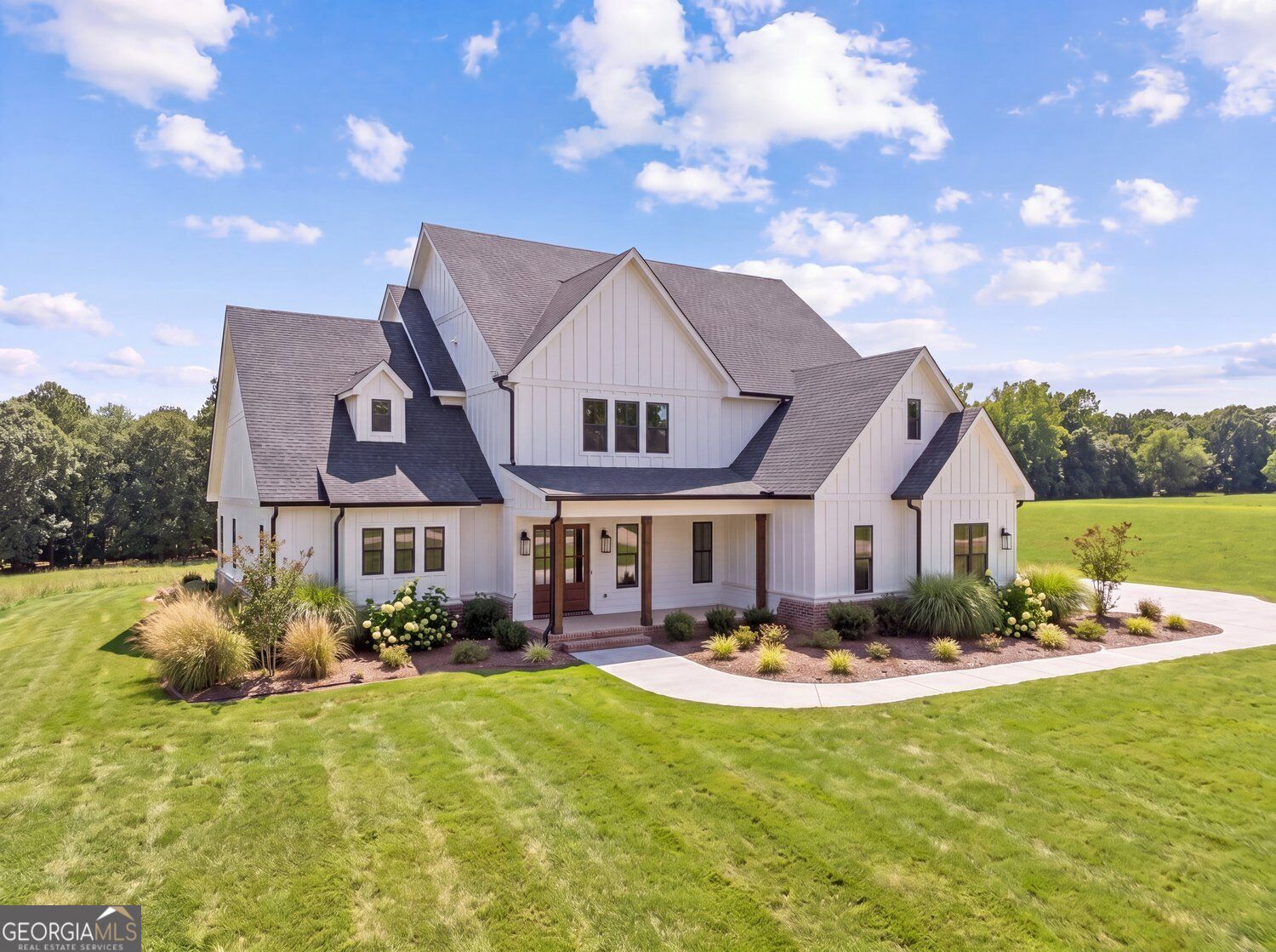 White farmhouse-style home with multiple gables, landscaped lawn, and curved front walk.