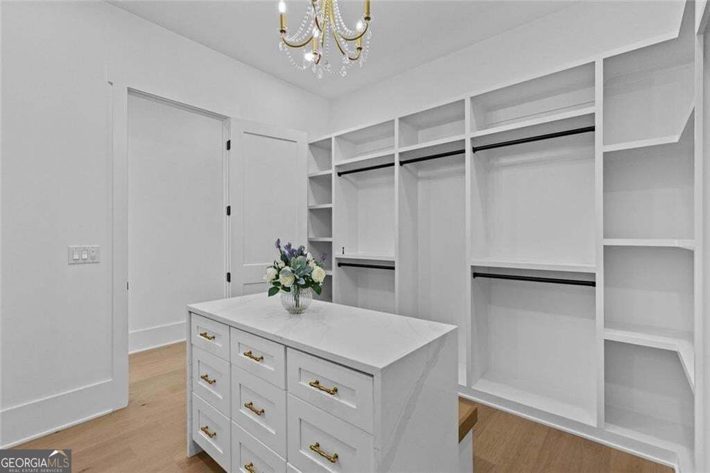 Walk-in closet with white built-ins, a central drawer island, and a chandelier.