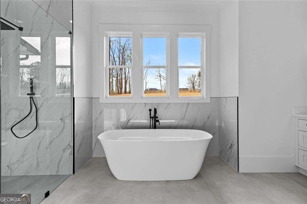 Bathroom with a freestanding soaking tub beneath three windows and a glass-enclosed shower.