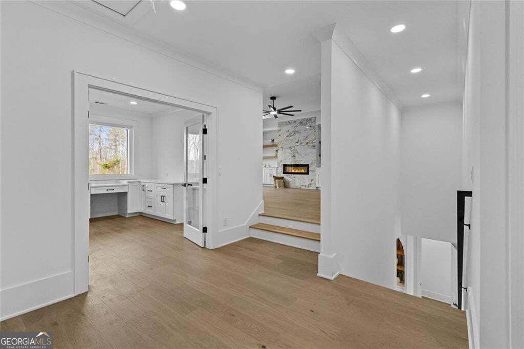 Entry hall with light wood floors, built-in desk, and steps leading to a living room with a marble fireplace.