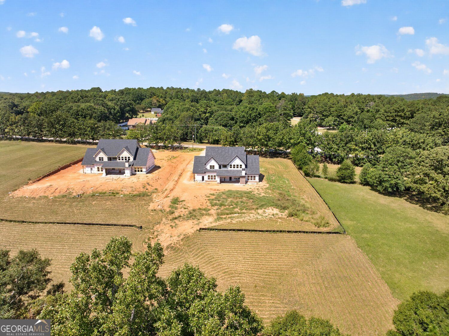 Aerial view of two homes under construction on a wooded rural property.