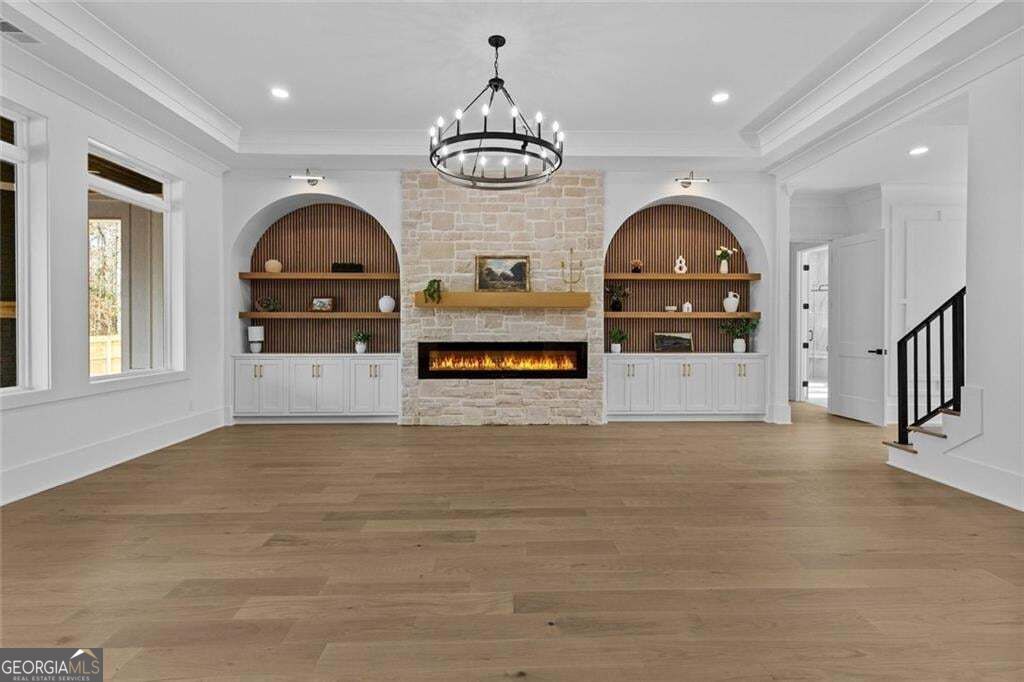 Living room with a pale stone fireplace, arched built-in shelves, and wide light-wood flooring.