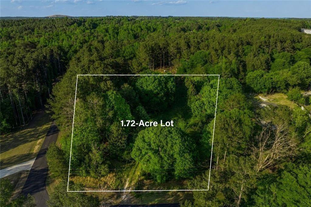 Aerial view of a wooded 1.72-acre lot outlined beside a curving road.