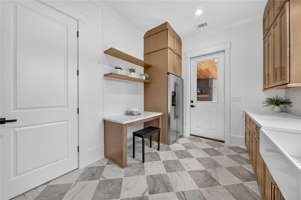 Kitchen with wood cabinets, stainless steel refrigerator, open shelves, and checkerboard tile floor.