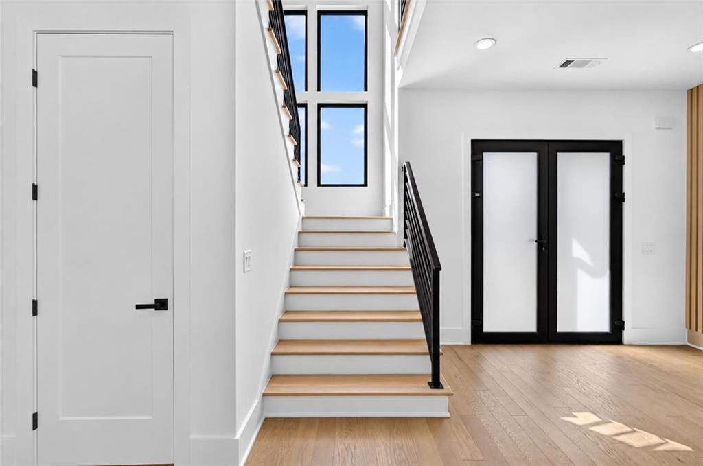Entry foyer with a staircase, tall windows, and black-framed double front doors.