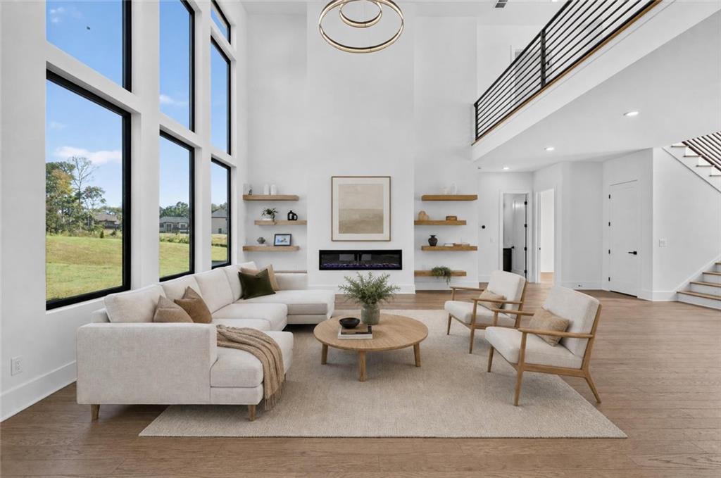 Double-height living room with tall windows, a cream sectional, floating shelves, and a linear fireplace.