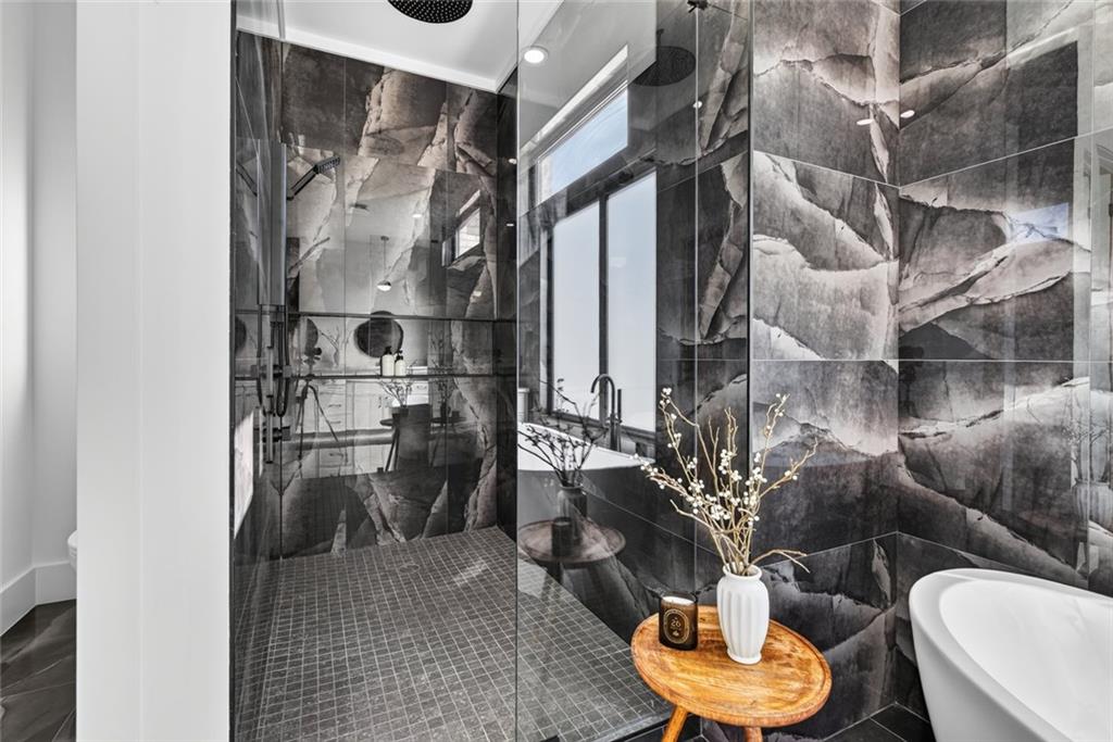 Modern bathroom with a glass shower, dramatic veined tile, and freestanding tub.