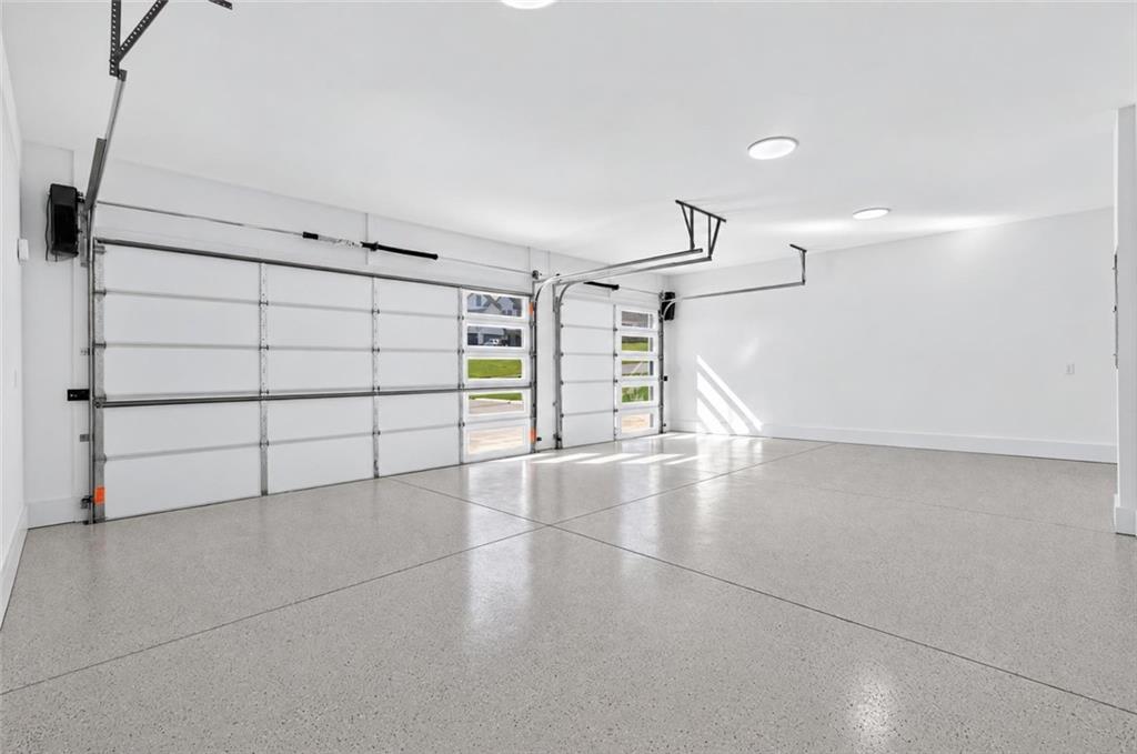 Empty garage with two windowed doors and a light gray speckled floor.