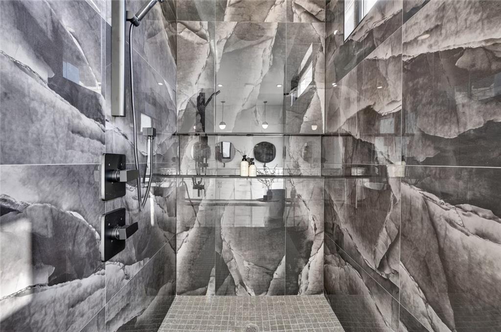 Walk-in shower with dramatic gray marble-patterned tile and black fixtures.