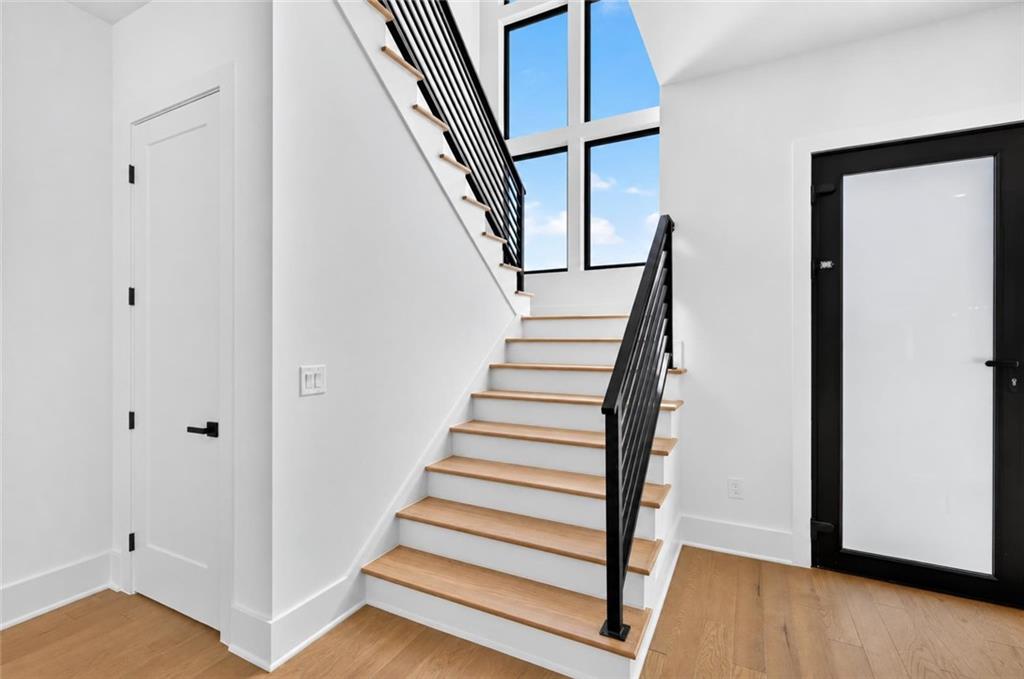 Entry foyer with a wood-tread staircase, black railings, and tall windows.