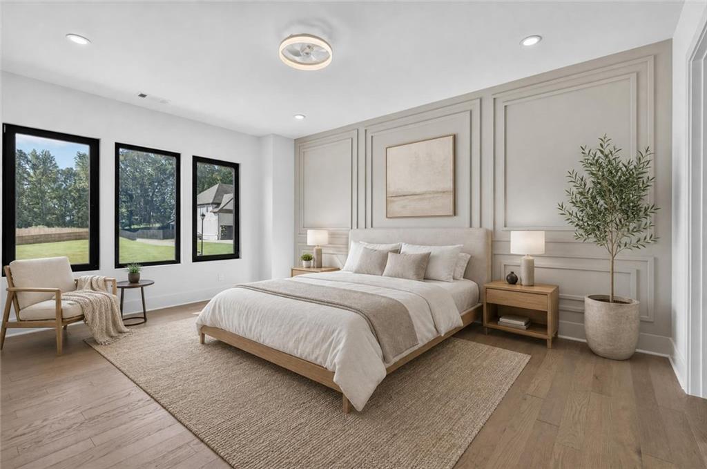 Staged bedroom with a large upholstered bed, paneled walls, and three tall windows.