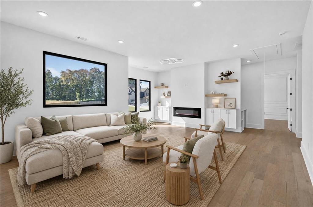 Staged living room with a cream sectional, woven rug, modern fireplace, and large windows.