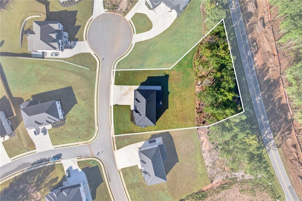 Aerial view of 125 Rocky Ridge Way, with the house and outlined lot beside a wooded road.