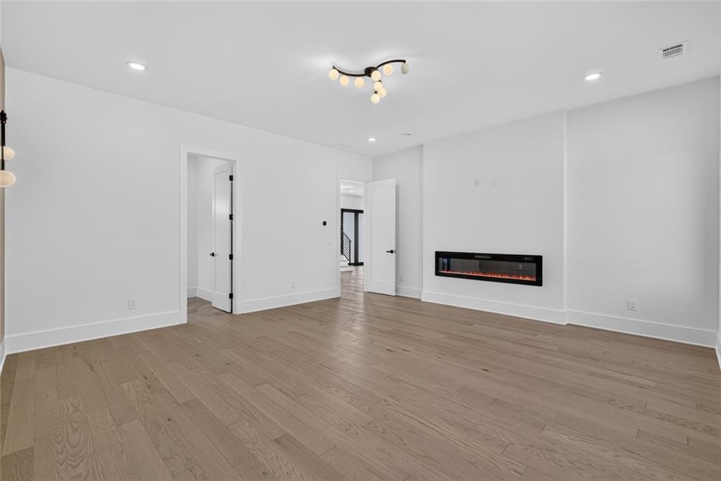 Empty living room with light wood floors and a wall-mounted electric fireplace.