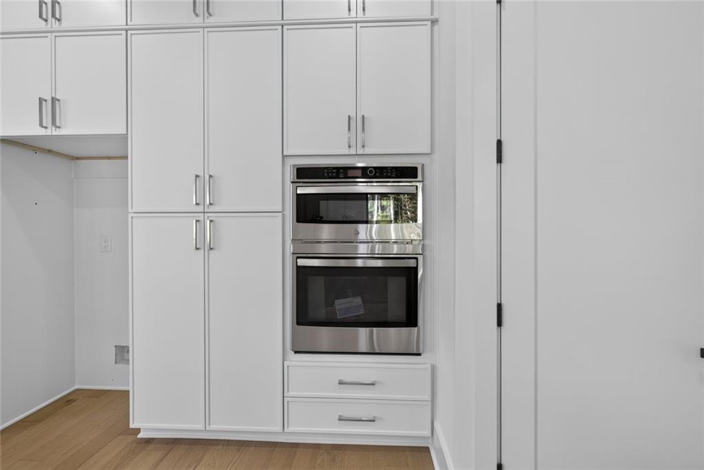 Kitchen with white floor-to-ceiling cabinets and a stainless-steel built-in microwave and oven.