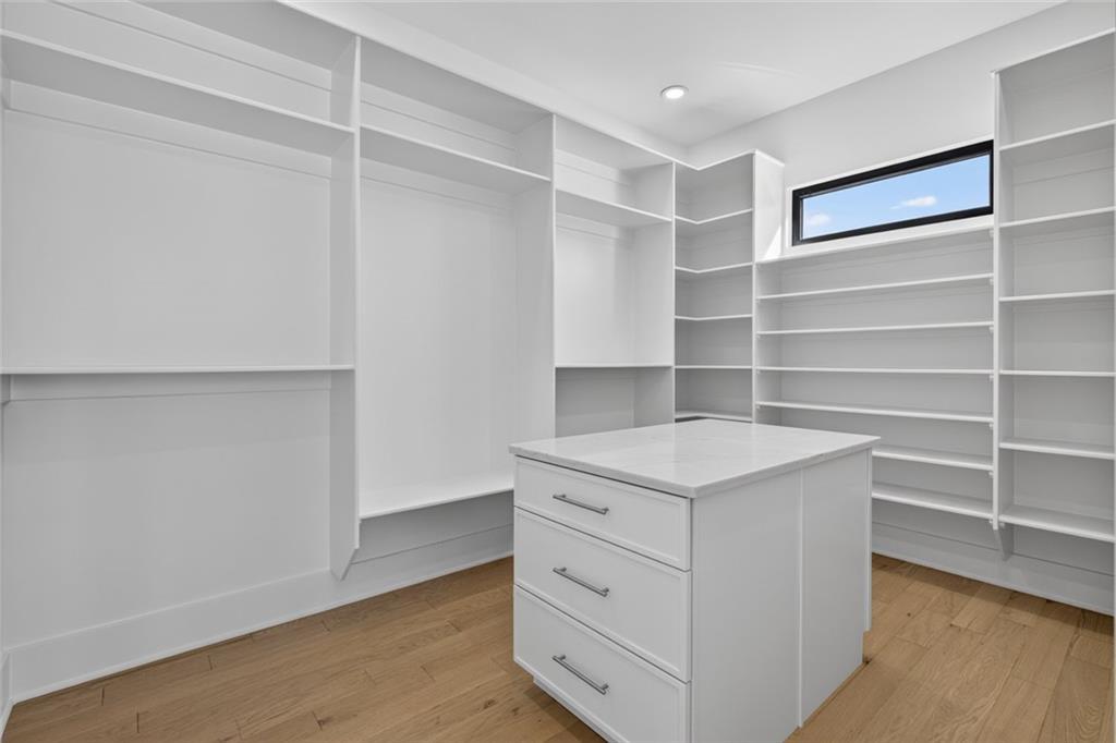 Walk-in closet with white built-in shelving and a central drawer island.