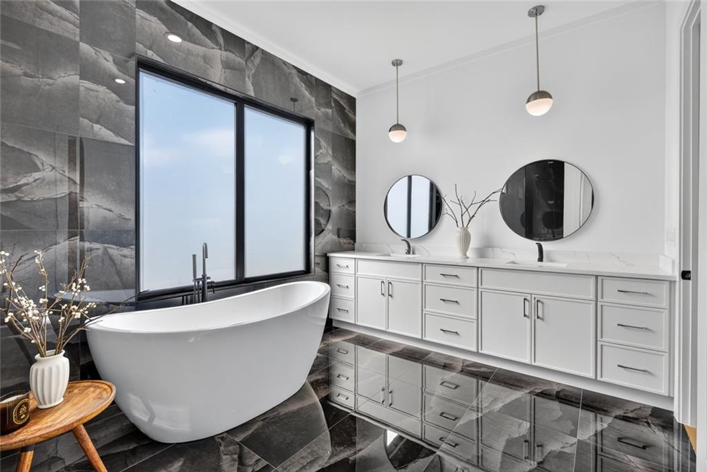 Modern bathroom with a freestanding tub, dramatic gray tile, and a long double vanity.