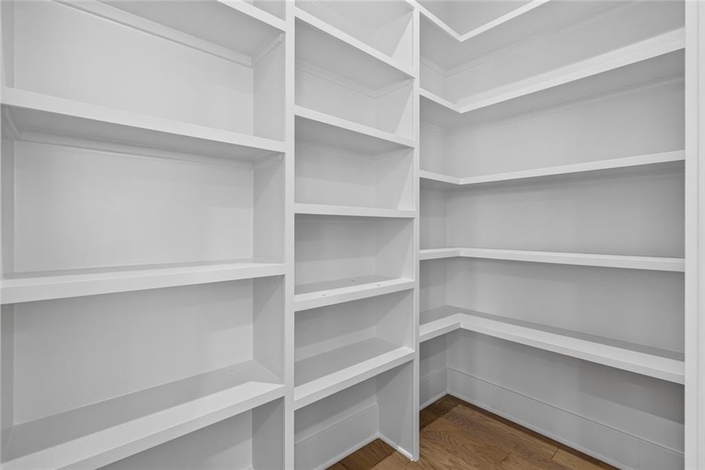 Walk-in closet with white built-in shelves and a wood floor.