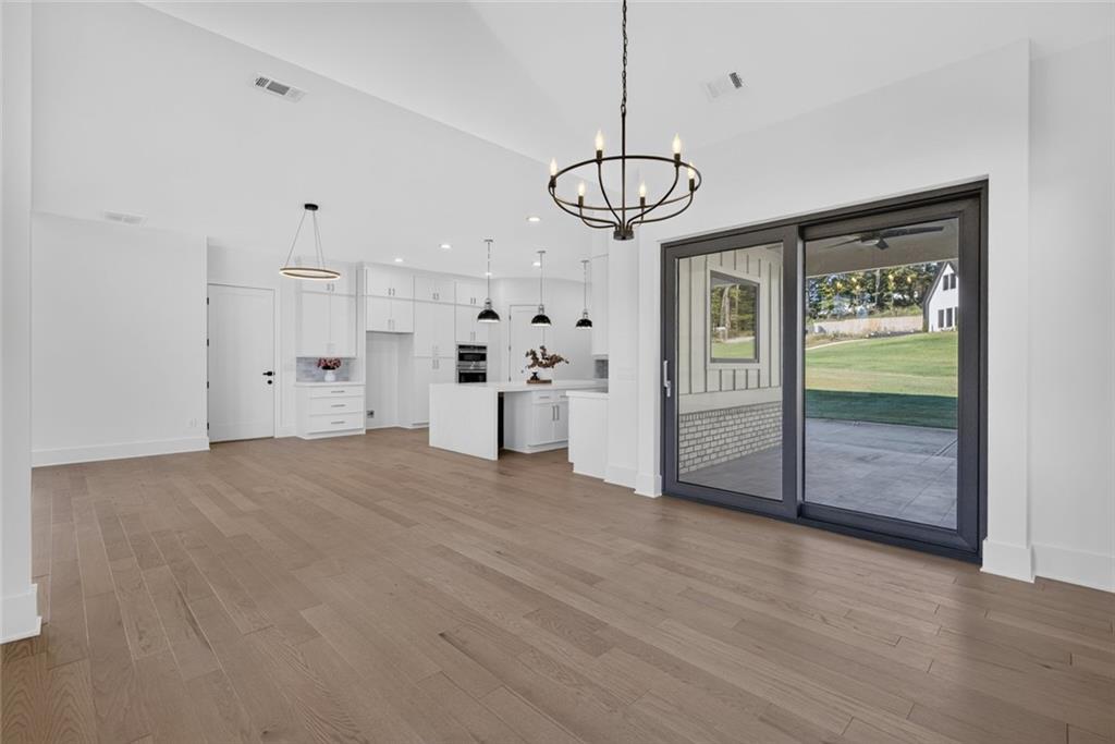 Open-plan kitchen and dining area with white cabinets, light wood floors, and sliding glass doors to a patio.