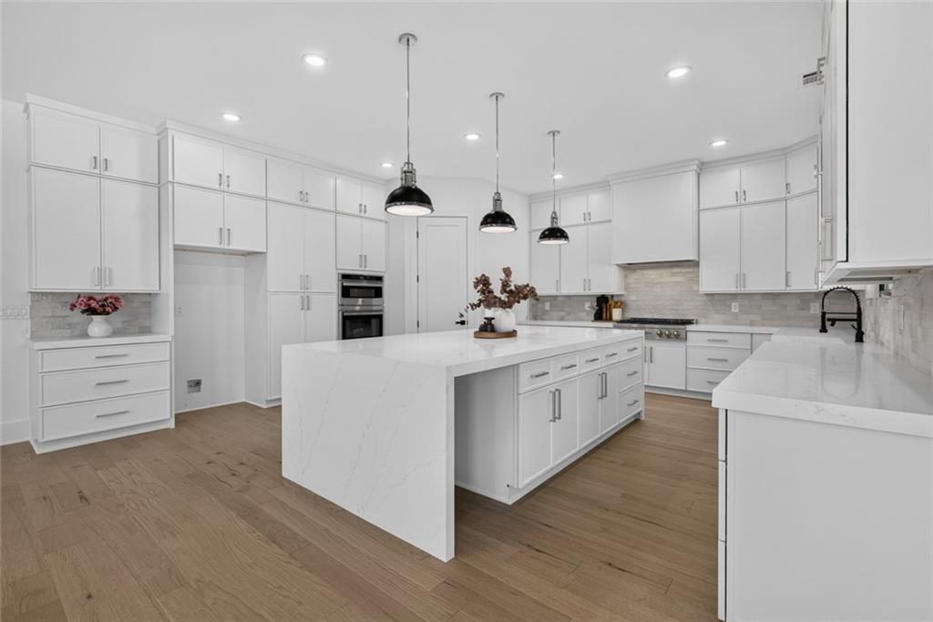 Modern kitchen with white cabinets, a large waterfall-edge island, and light wood floors.