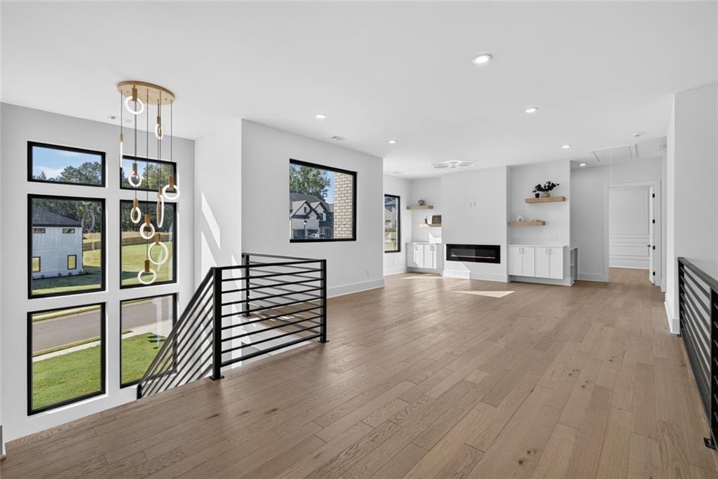 Vacant living area with large windows, light wood floors, and a modern fireplace.