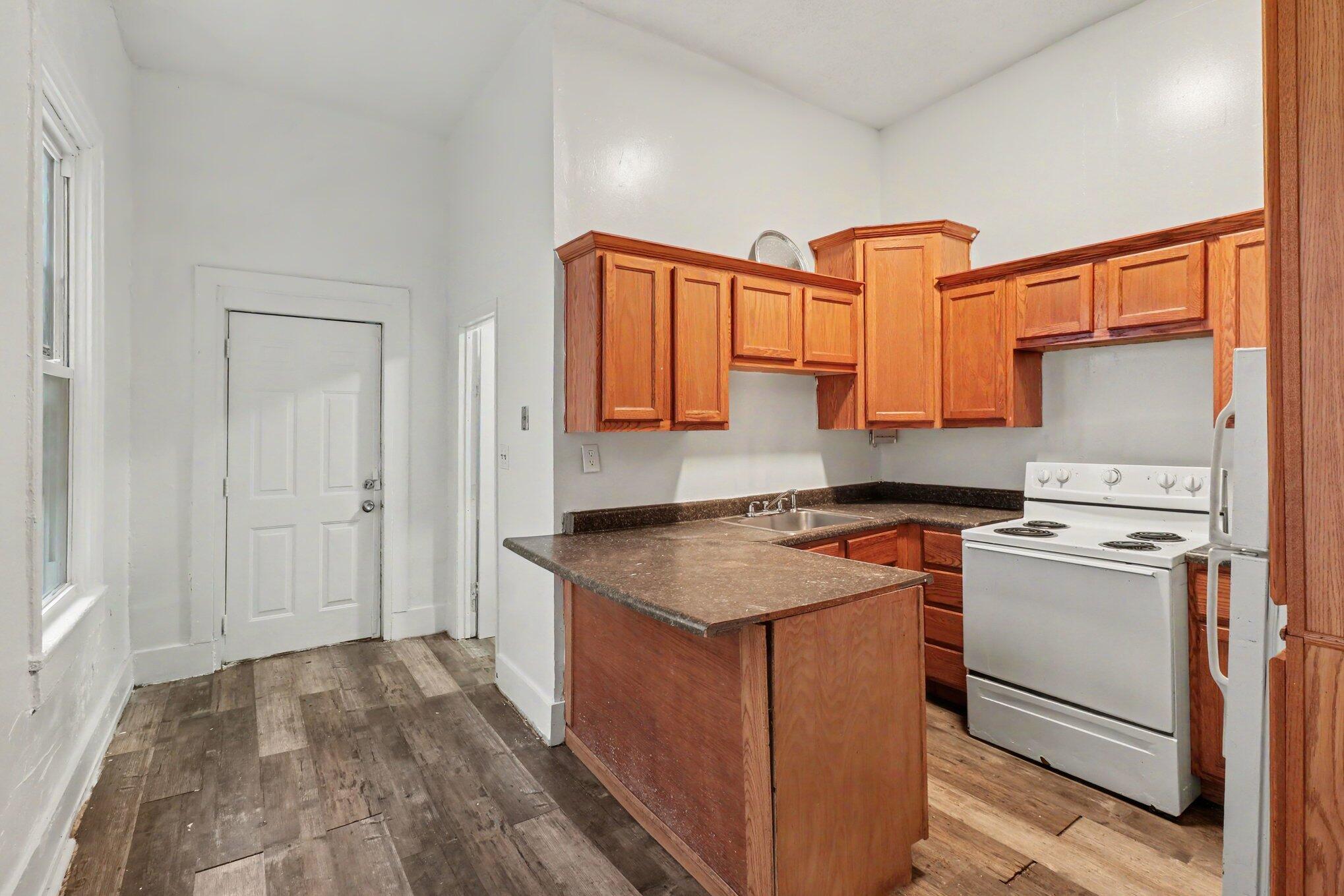 Kitchen with reddish wood cabinets, a brown peninsula counter, and white appliances.